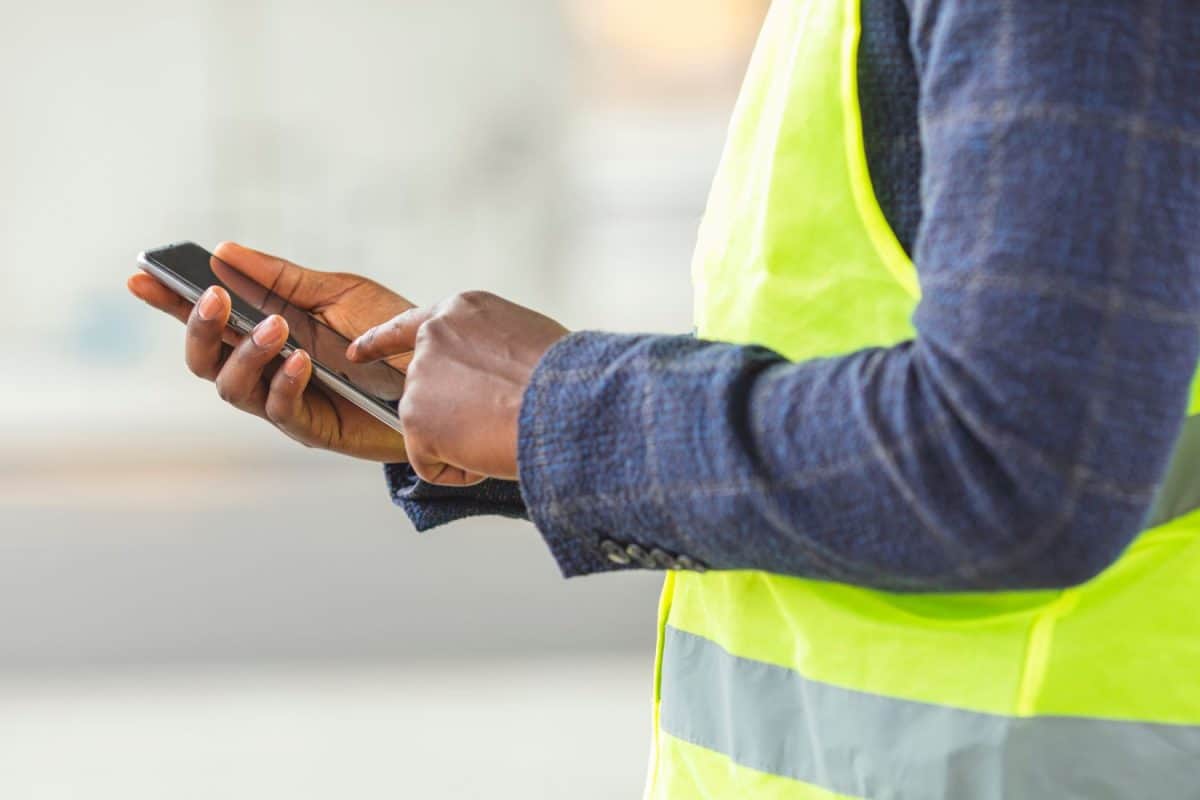 Construction worker typing on a smartphone. Fueling innovation with technology. Engineer, architect or construction worker on a construction site of a new building.