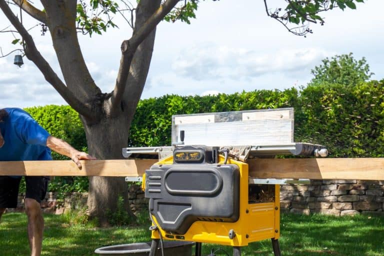 Joiner, Man scouring a wooden board on a thickness machine in garden. Carpenter working with electric planer on wooden beam, plank. - How To Use A DeWalt Planer [Step By Step Guide]