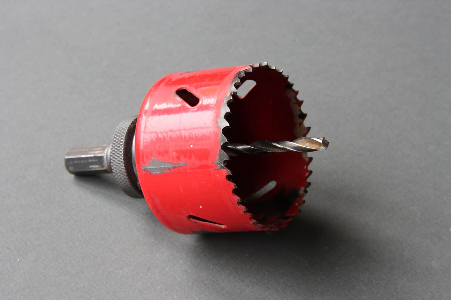 Red drill bit for drilling round holes in metal and other materials 