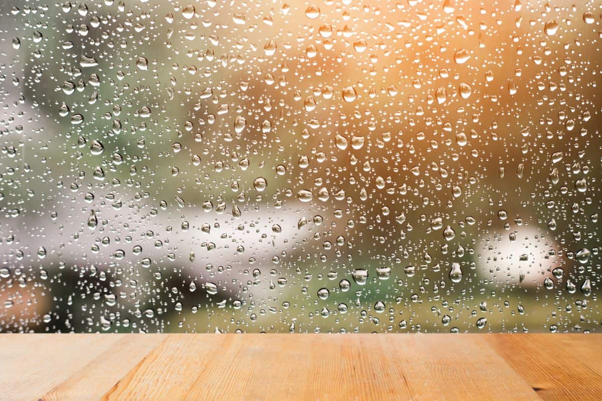 Wood table top on rain drops on clear window - can be used for display or montage your products