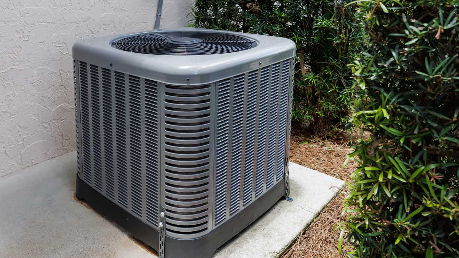Modern HVAC air conditioner unit on concrete slab outside of house