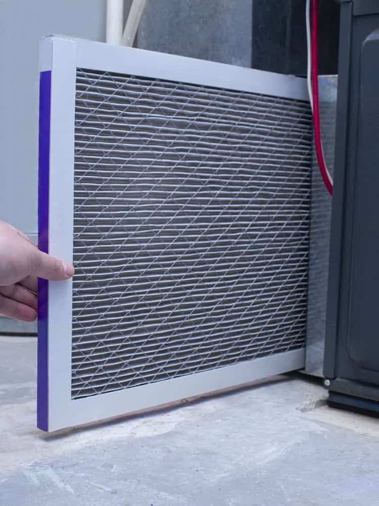 A person changing an air filter on a high efficiency furnace

